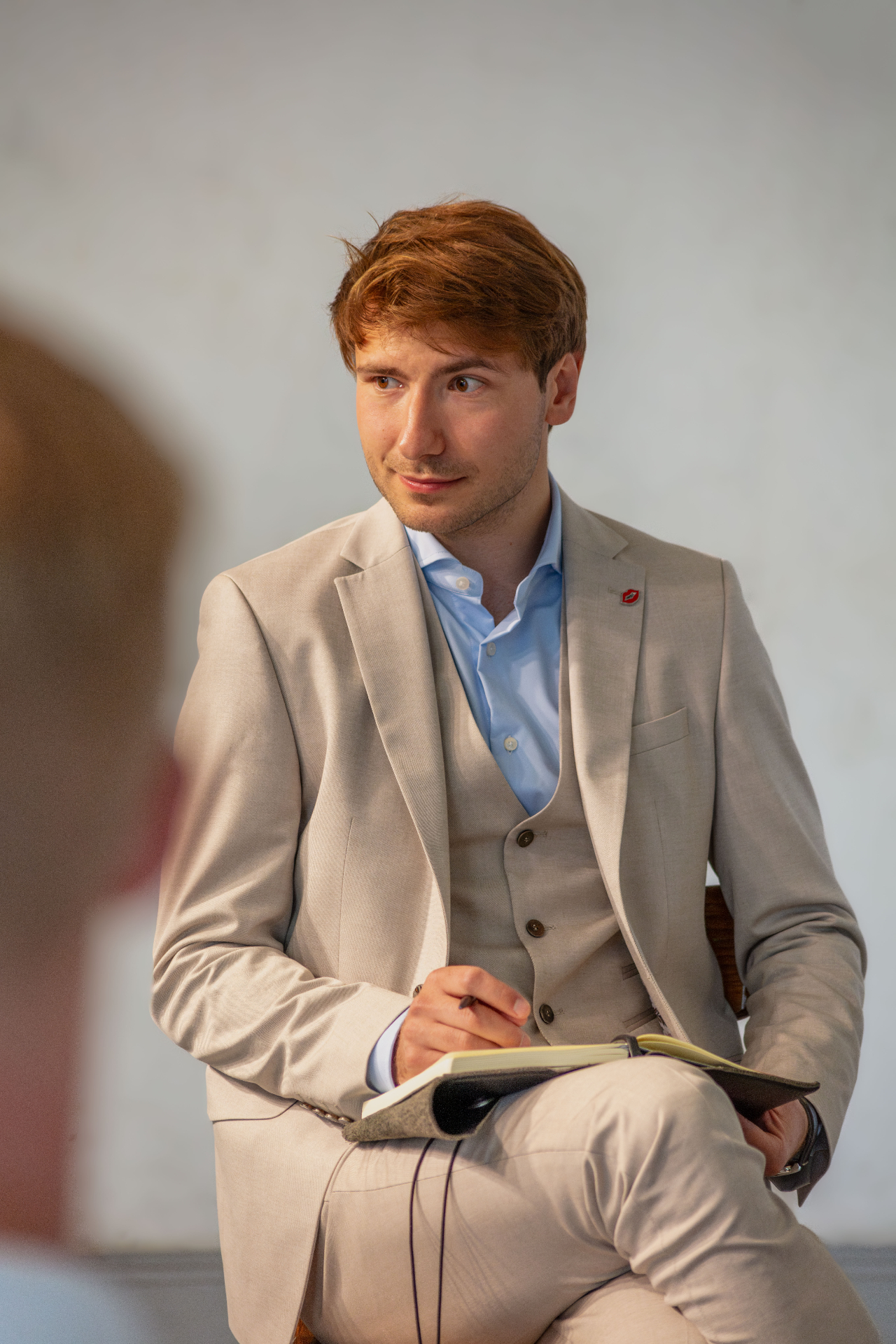 Simon Dworaczek im Gespräch, mit Notizbuch — nachdenklich zuhörend