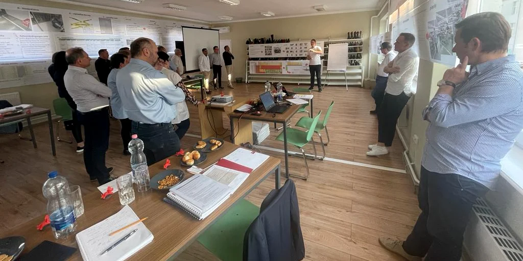 Gruppe von Mitarbeitenden und Führungskräften bei einer gemeinsamen Präsentation und Diskussion in einem Workshopraum.